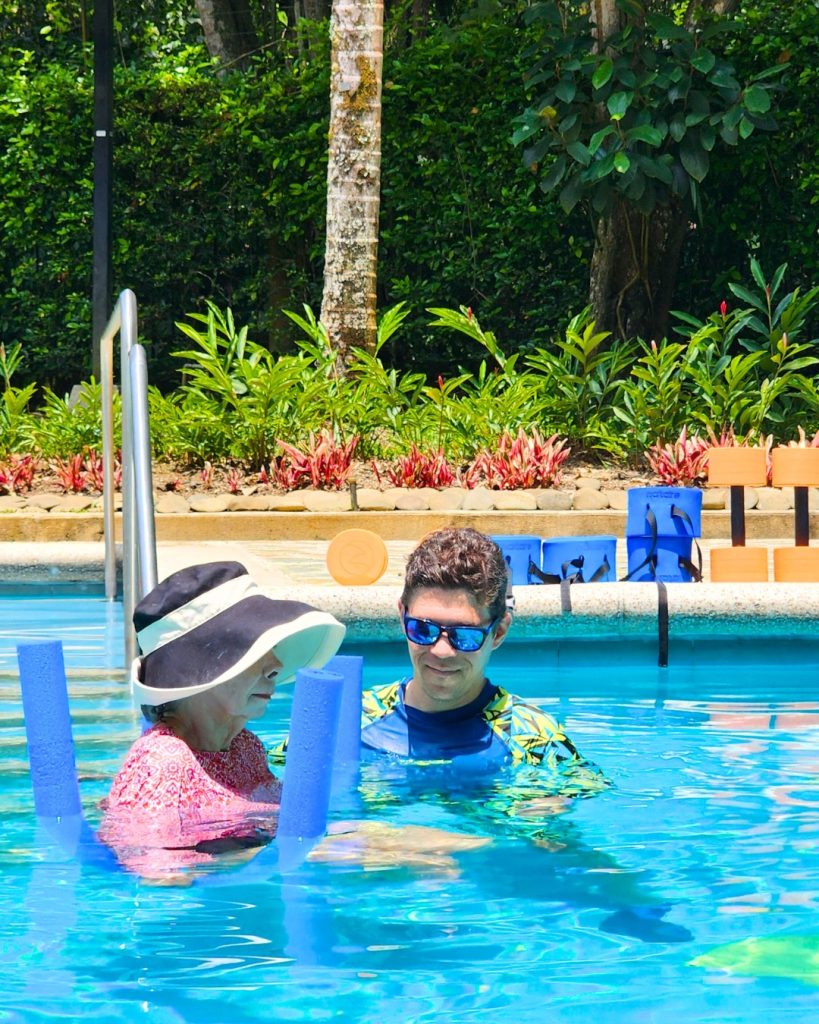 Instructor de AUA FIT guiando a una mujer mayor en una sesión personalizada de AquaFitness del Plan Impulso en Cali, Colombia.