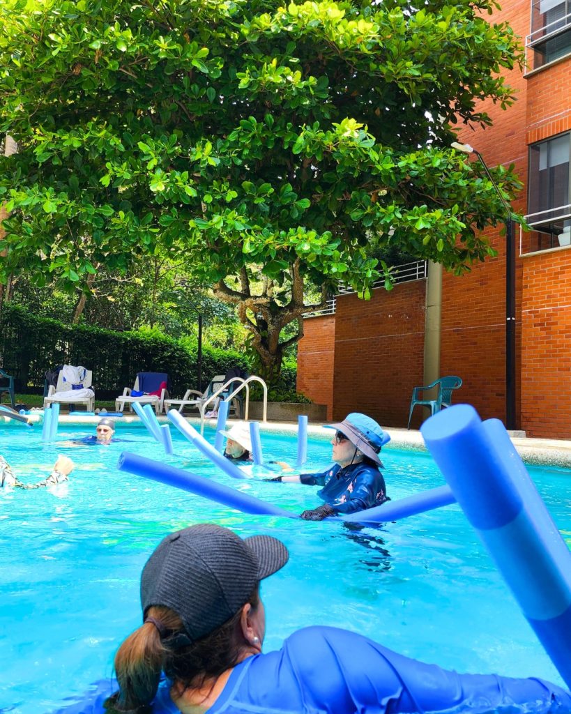 Mujeres disfrutando de una clase grupal de AquaFitness del Plan Ritmo de AUA FIT, usando flotadores azules en una piscina en Cali.