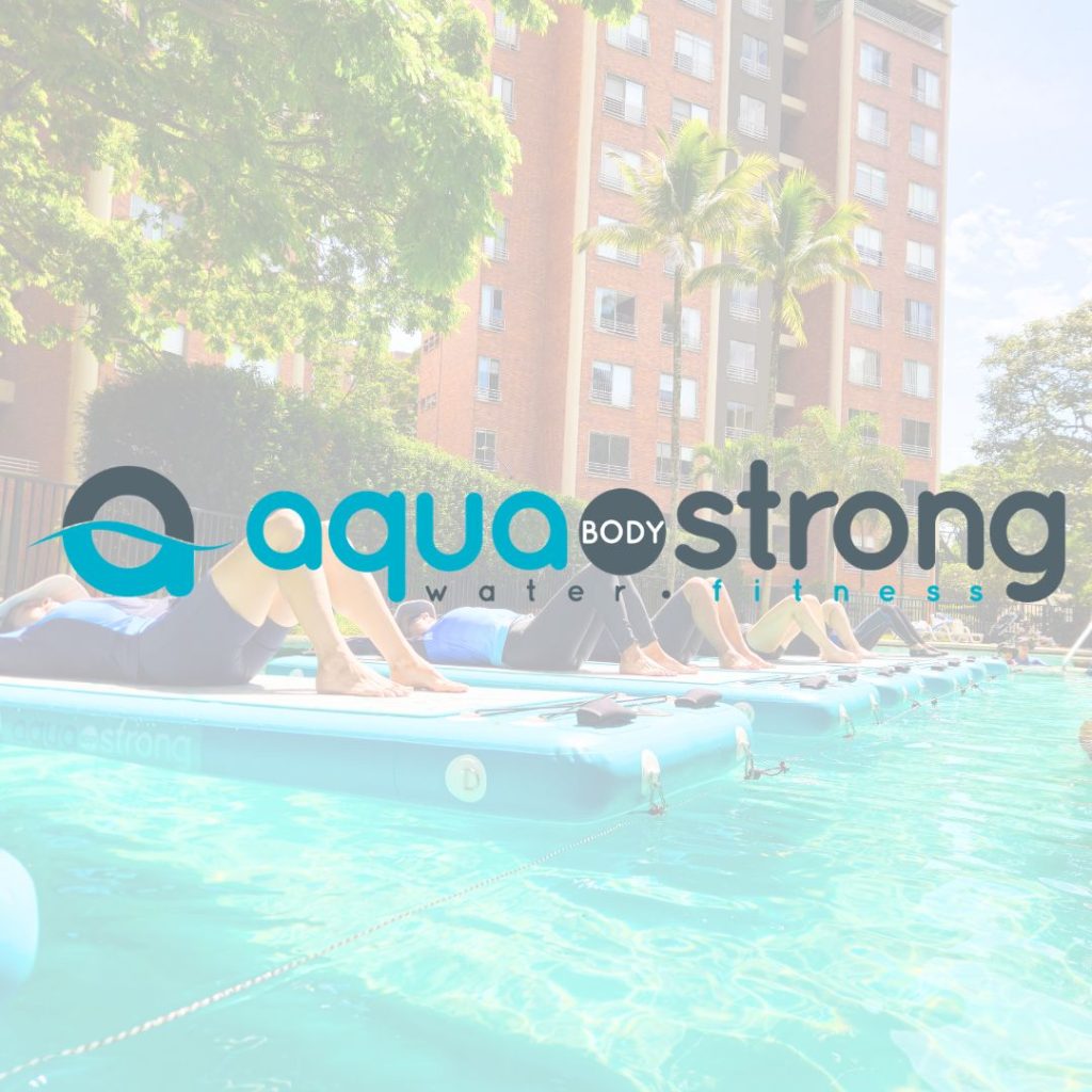 Grupo de personas entrenando sobre tablas flotantes en una piscina. Logo oficial de Aqua Body Strong, partner exclusivo y metodología internacional de AUA FIT en Cali, Colombia.